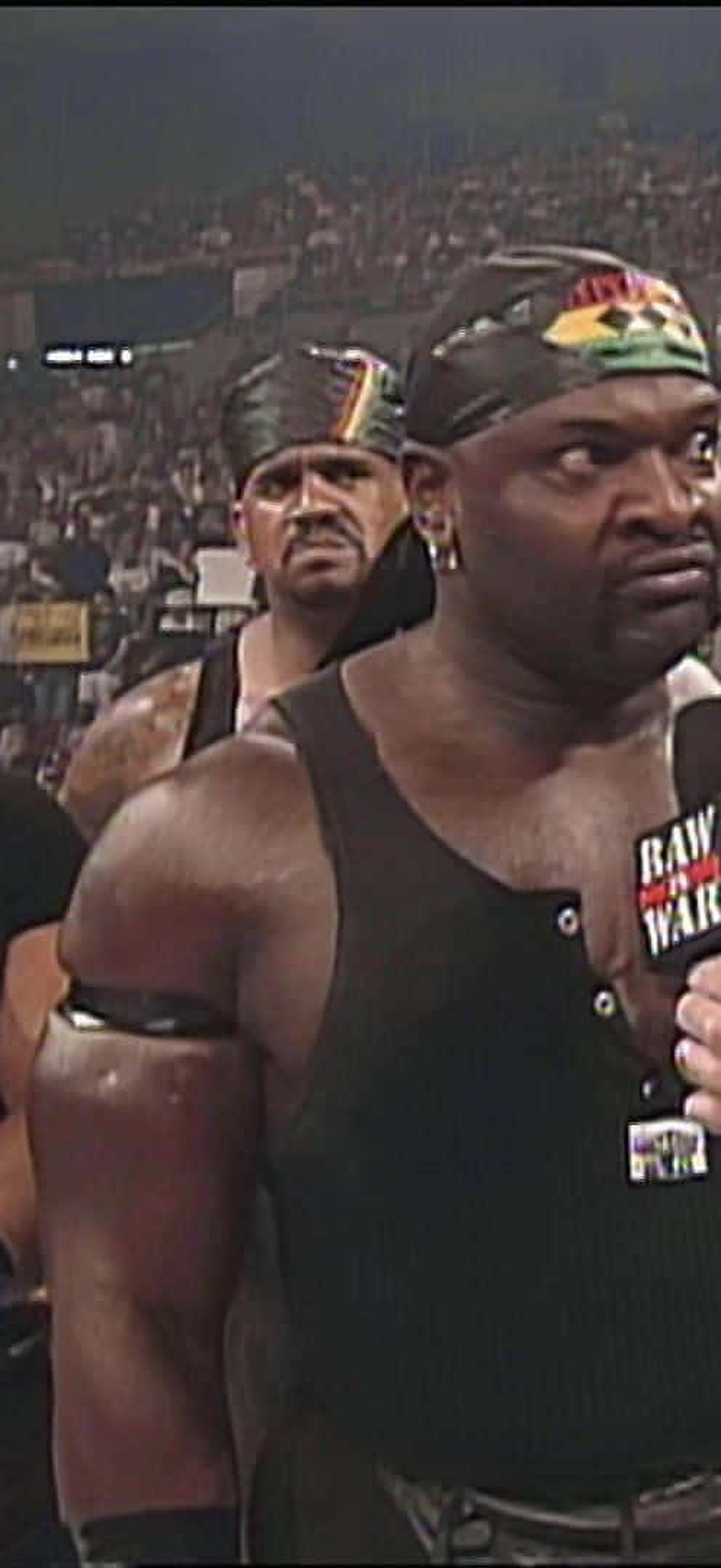 Four WWE wrestlers in black gear during an arena interview with a crowd behind them.