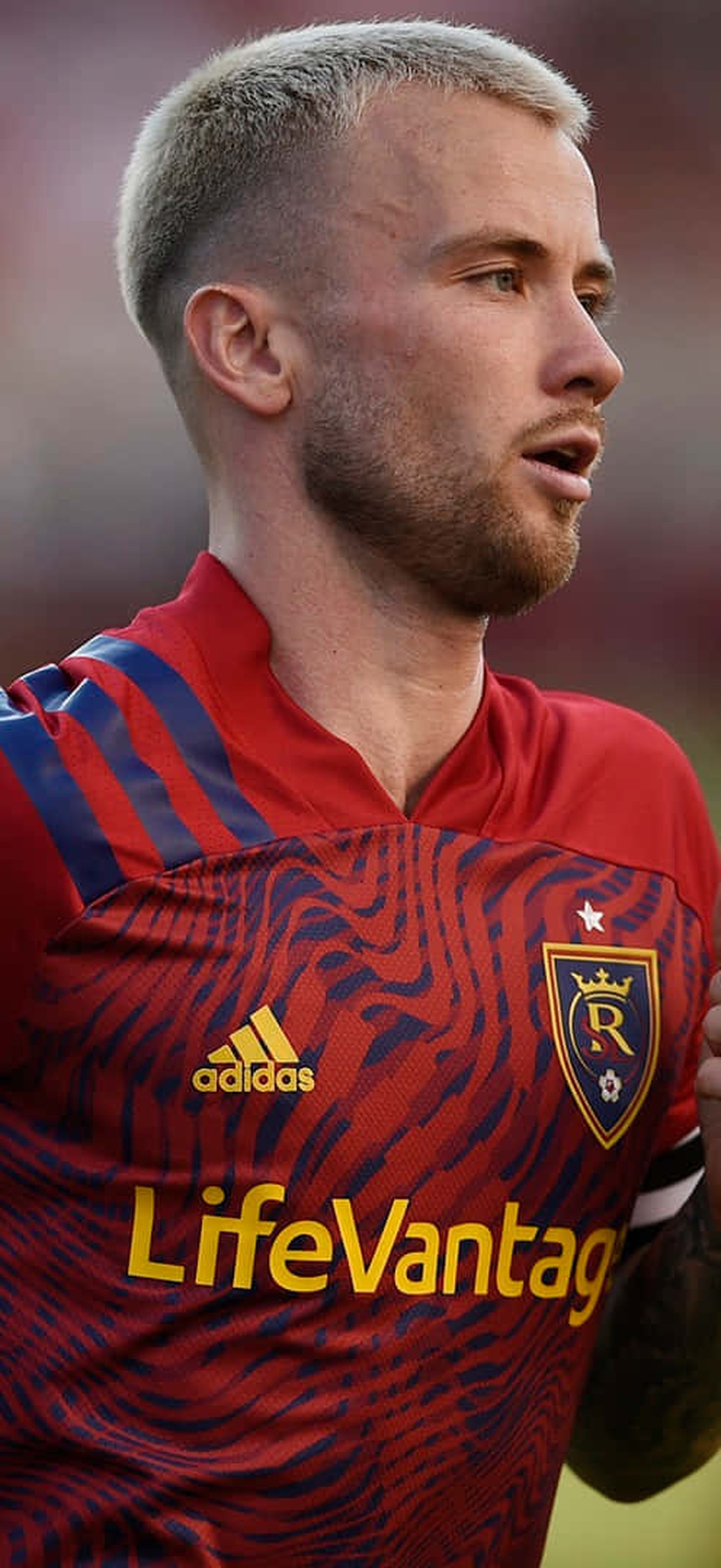 Soccer player in red jersey running on grass field during game.