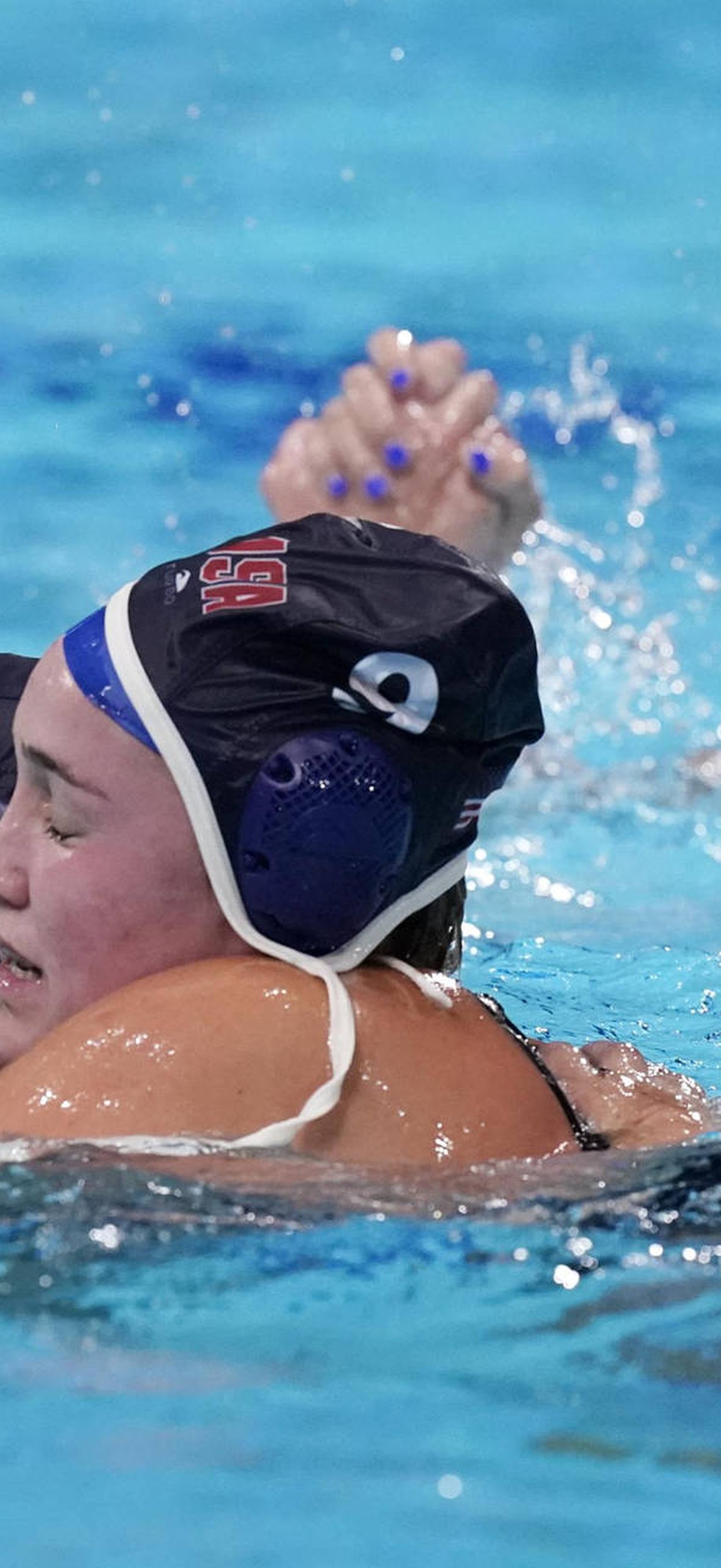 Water polo athletes celebrating in pool with splashing water.