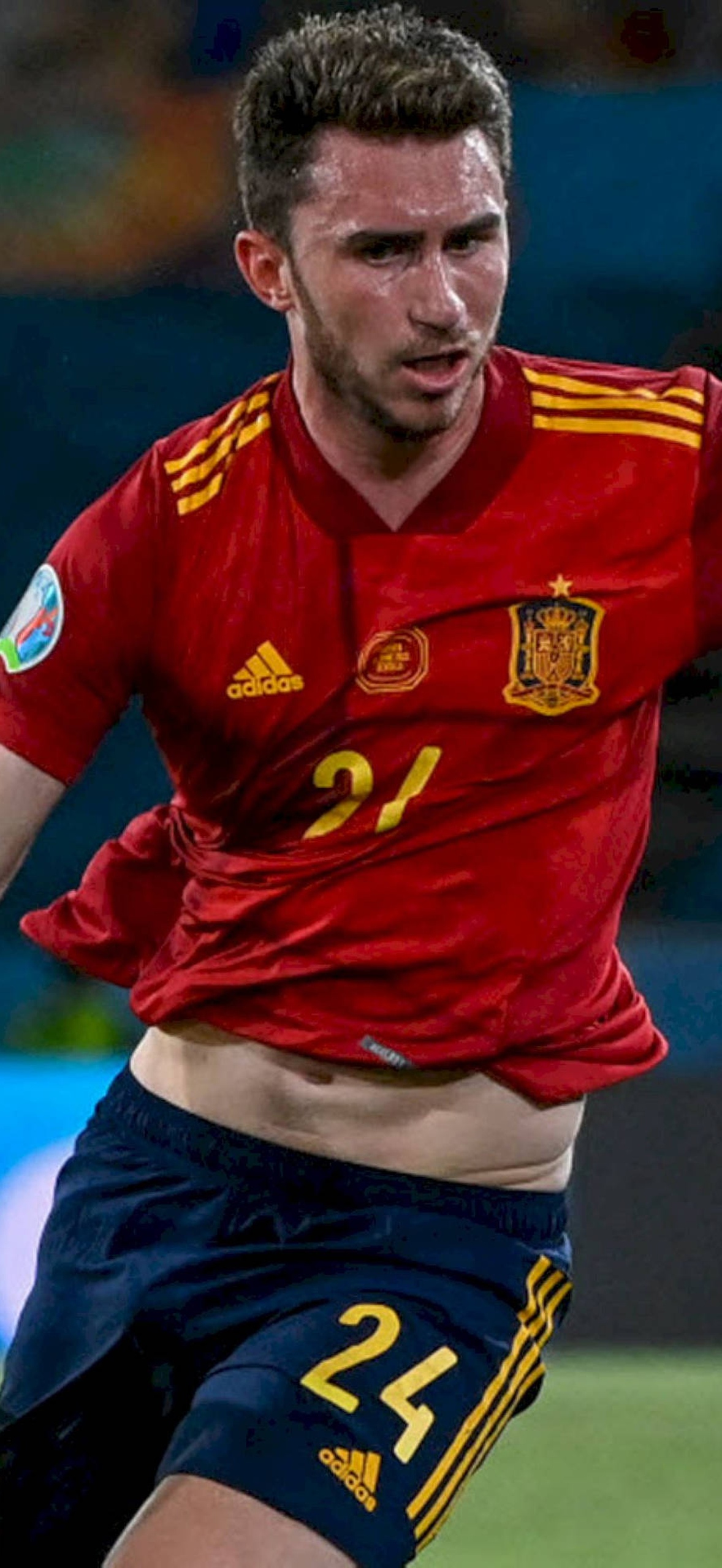 Spanish soccer player number 21 in red jersey competing intensely during a night match.