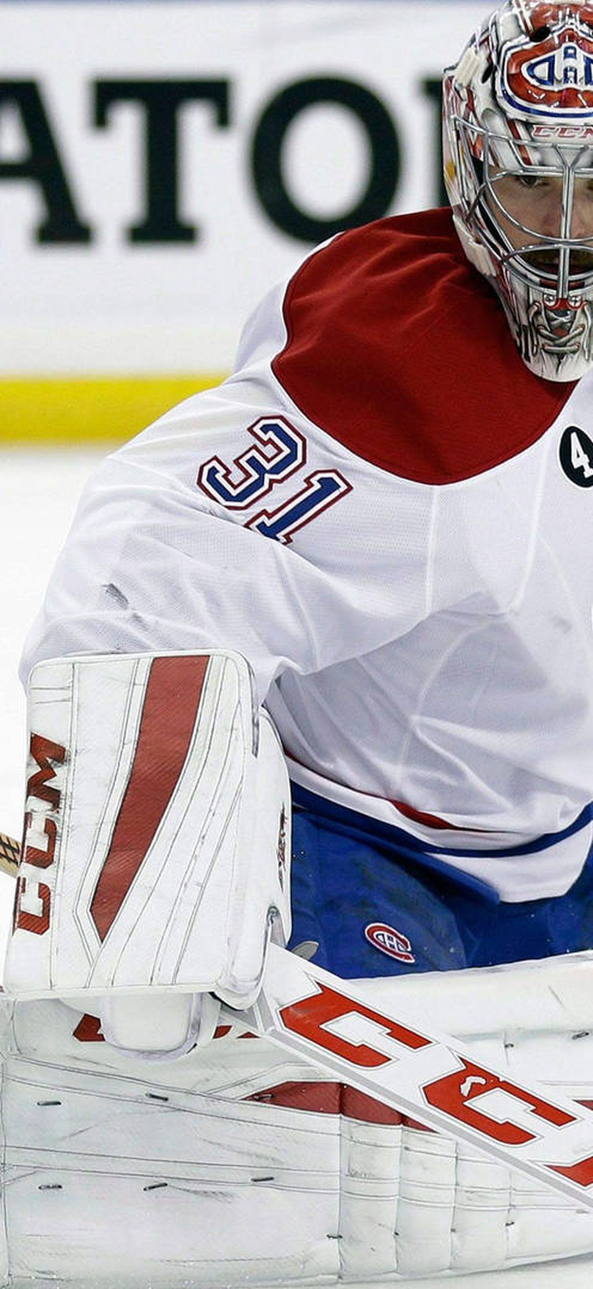 Hockey goalie in full gear crouching on ice ready to block puck.
