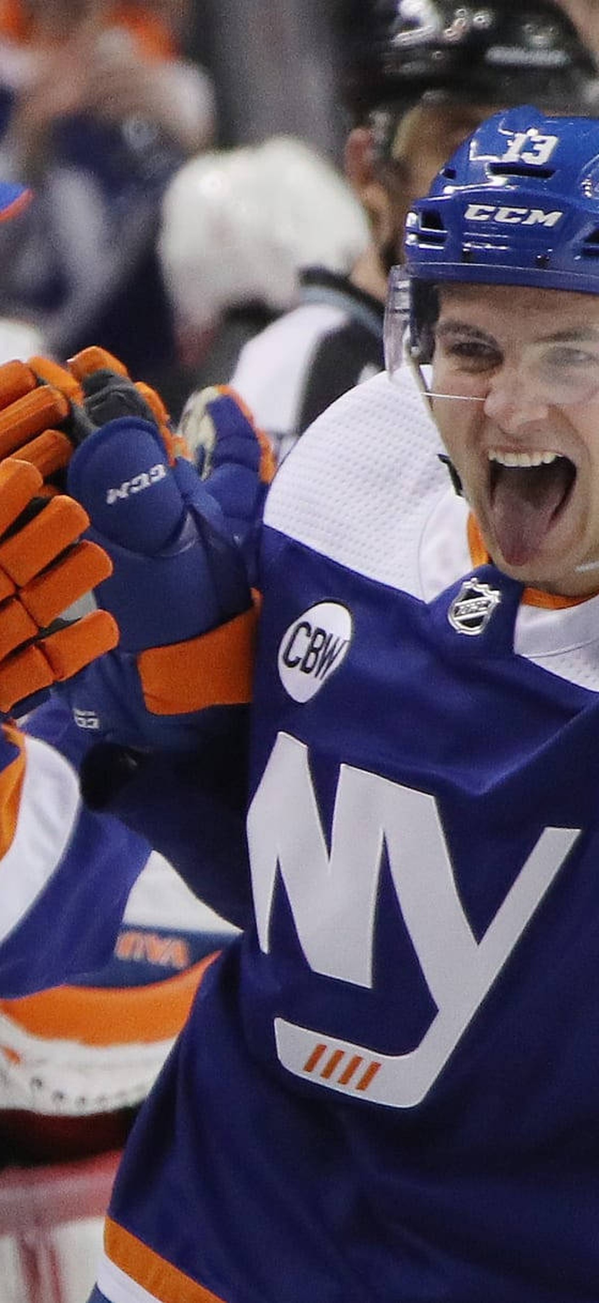 Hockey player celebrates with teammates during game wearing blue and orange uniform.