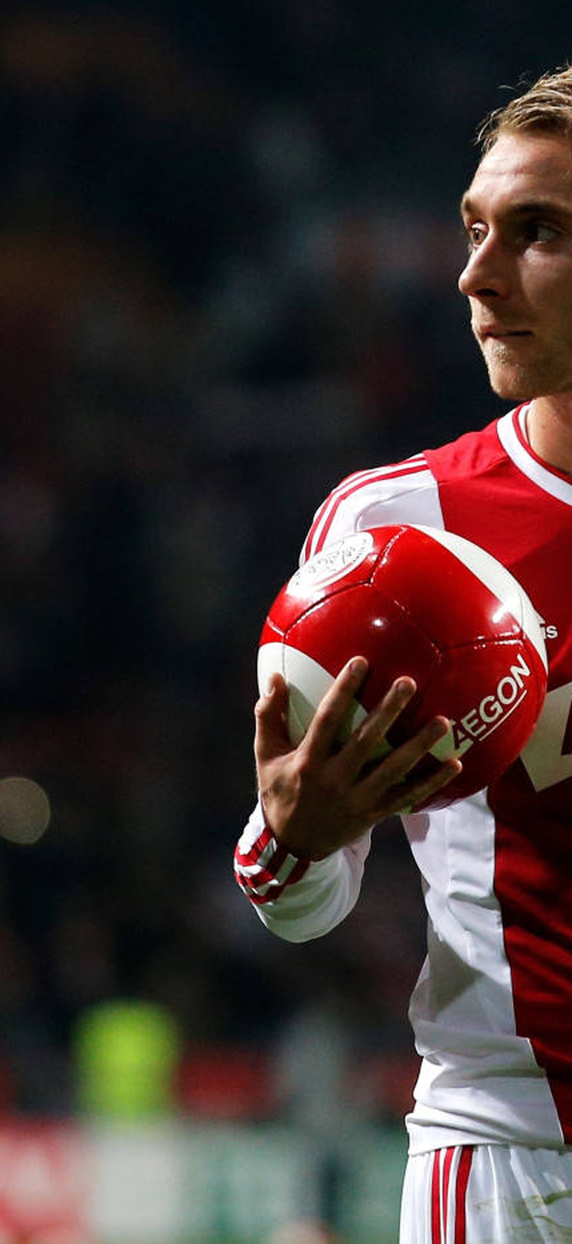 Soccer player holding ball in stadium under bright lights