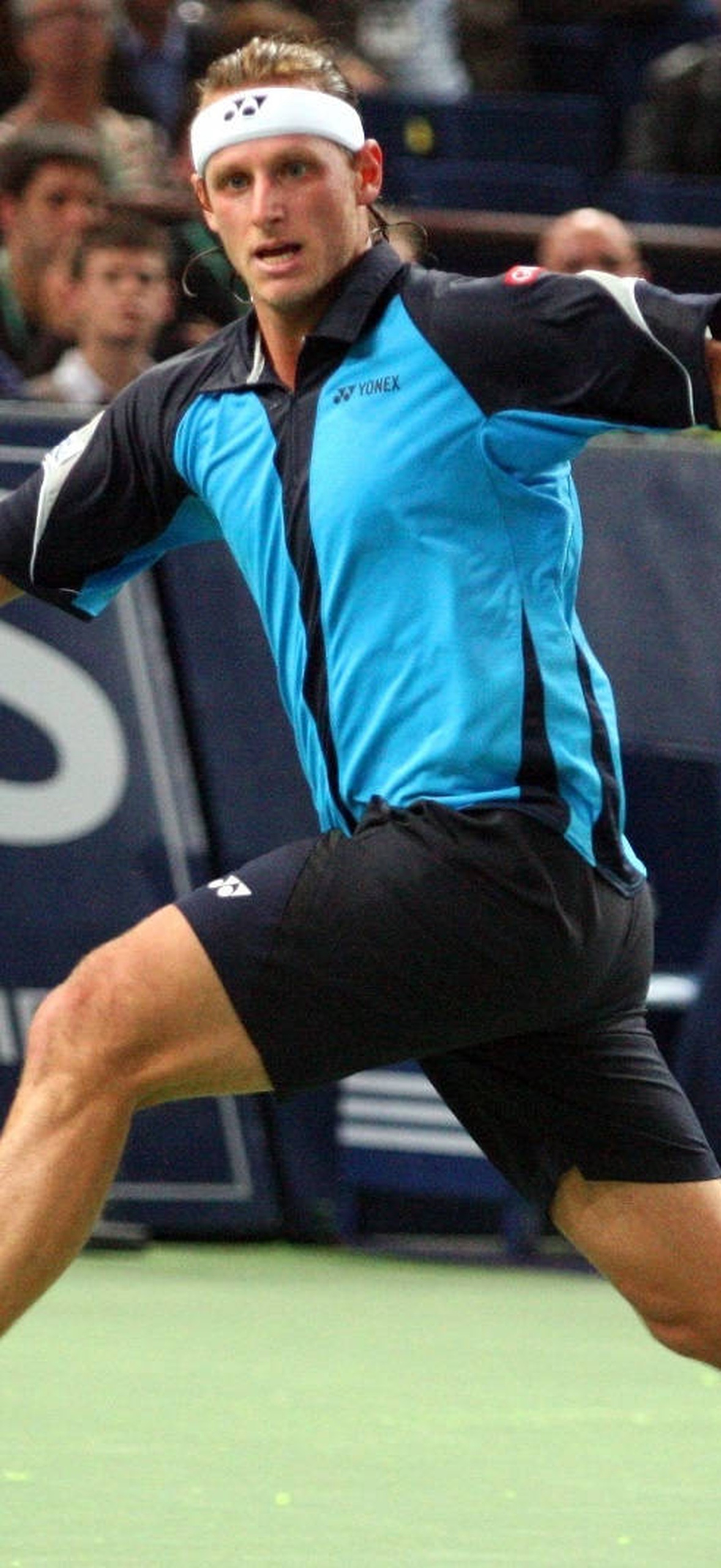 Tennis player lunges to hit a ball during a match.