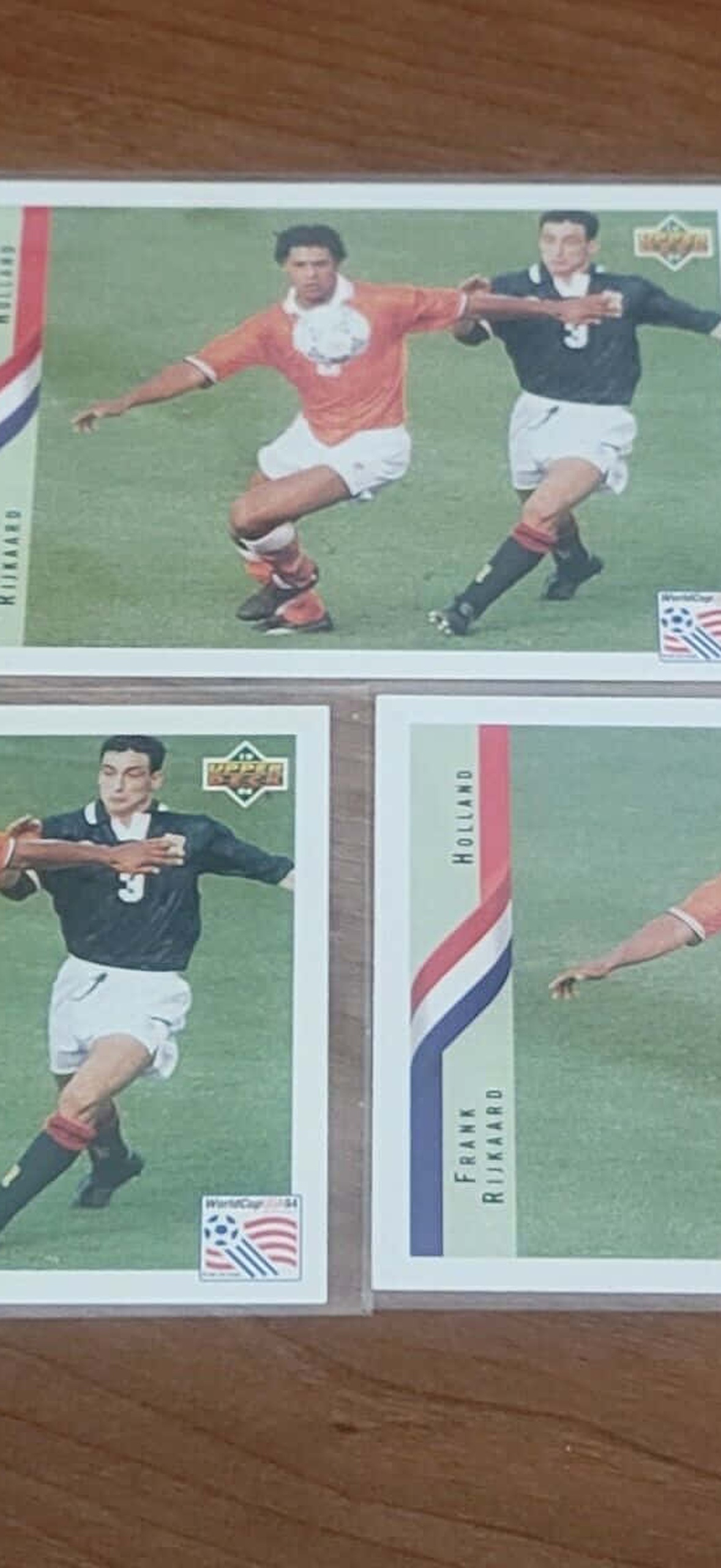 Three vintage soccer trading cards on a wooden table.