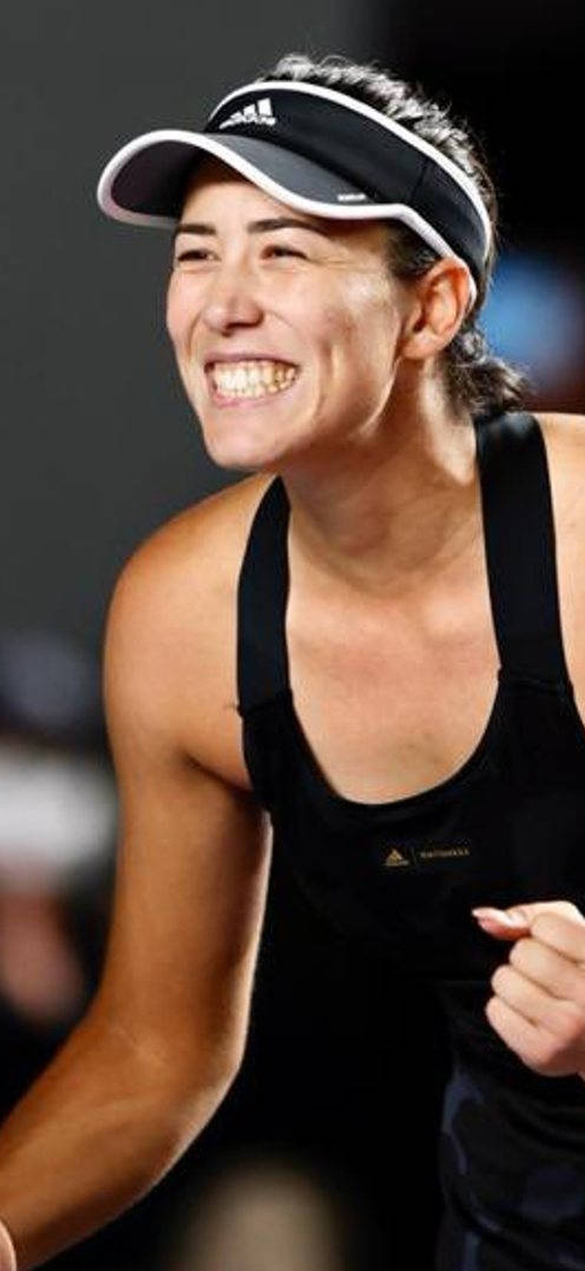 Tennis player cheering with clenched fist after winning point at night match.
