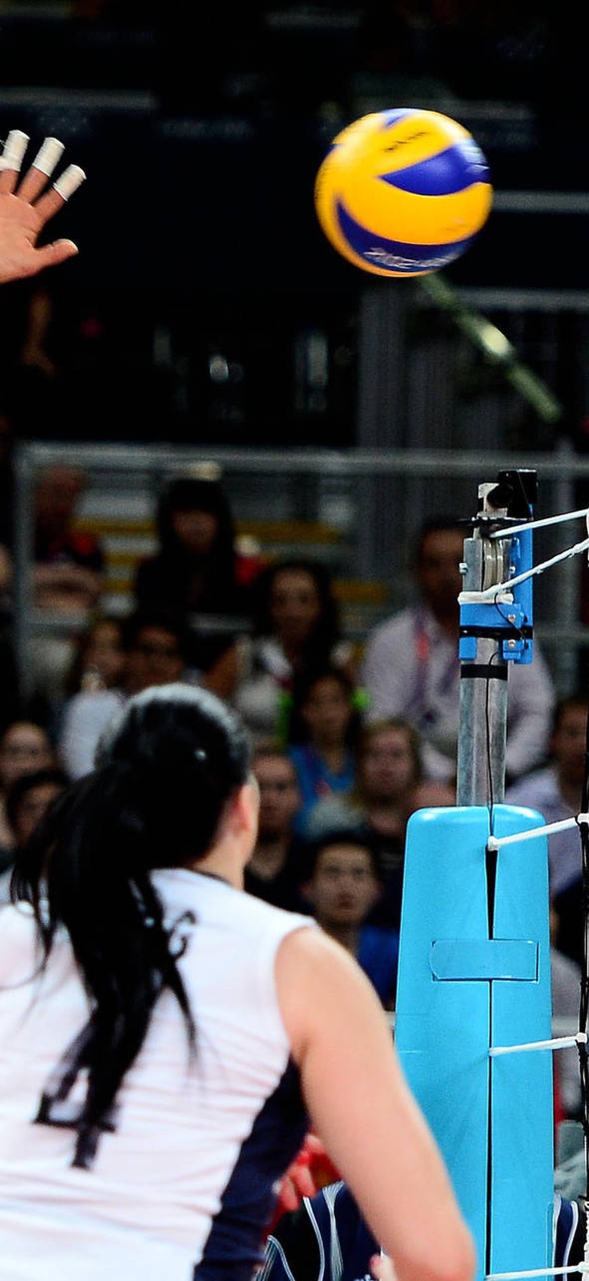 Female volleyball player spiking the ball during a match.