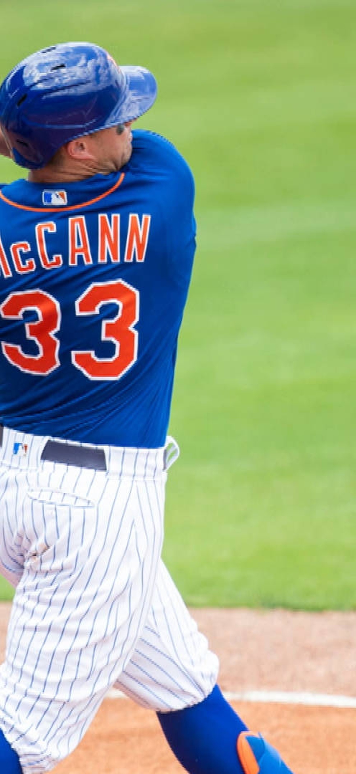 Baseball player swinging bat during daytime game on grass field.