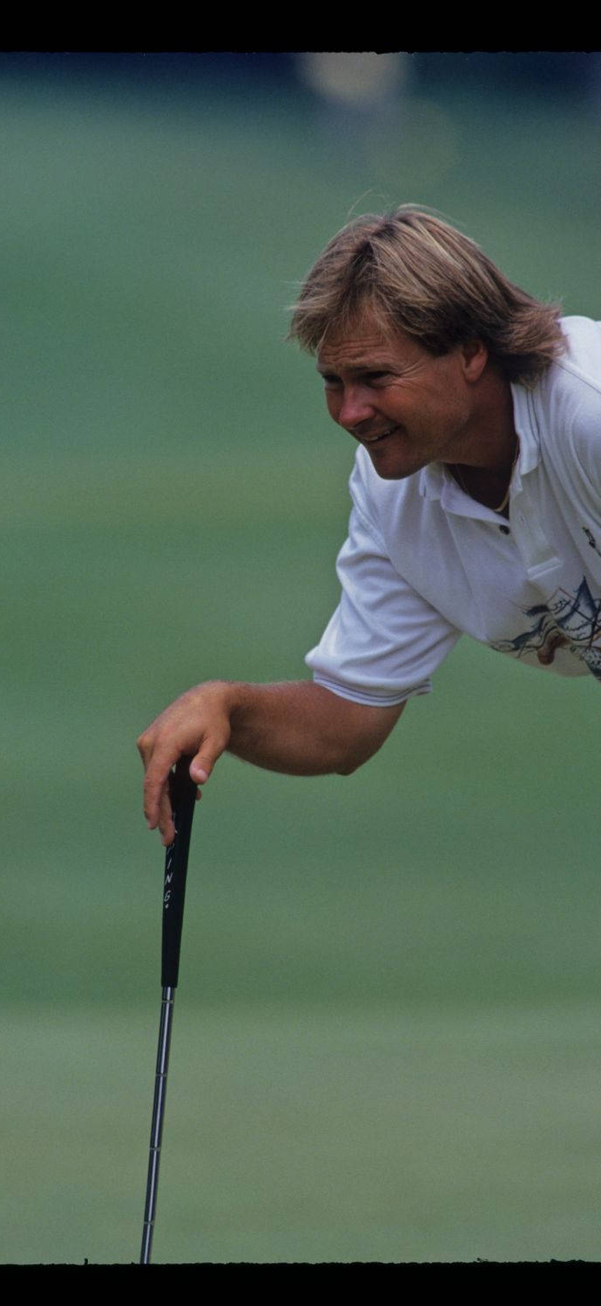 Golfer smiling while holding club on green course