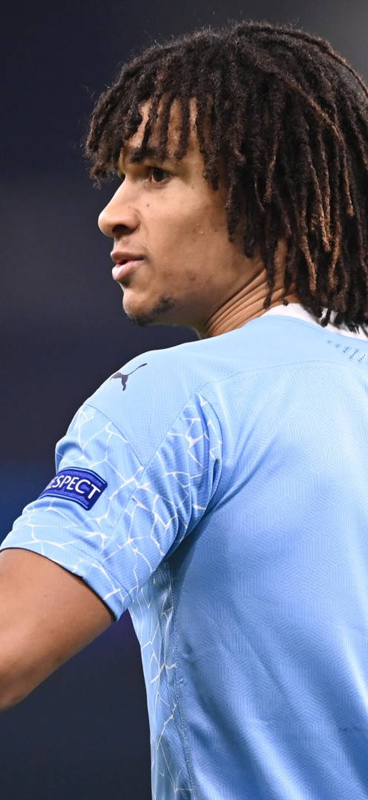 Soccer player in light blue jersey pointing upward during a match.