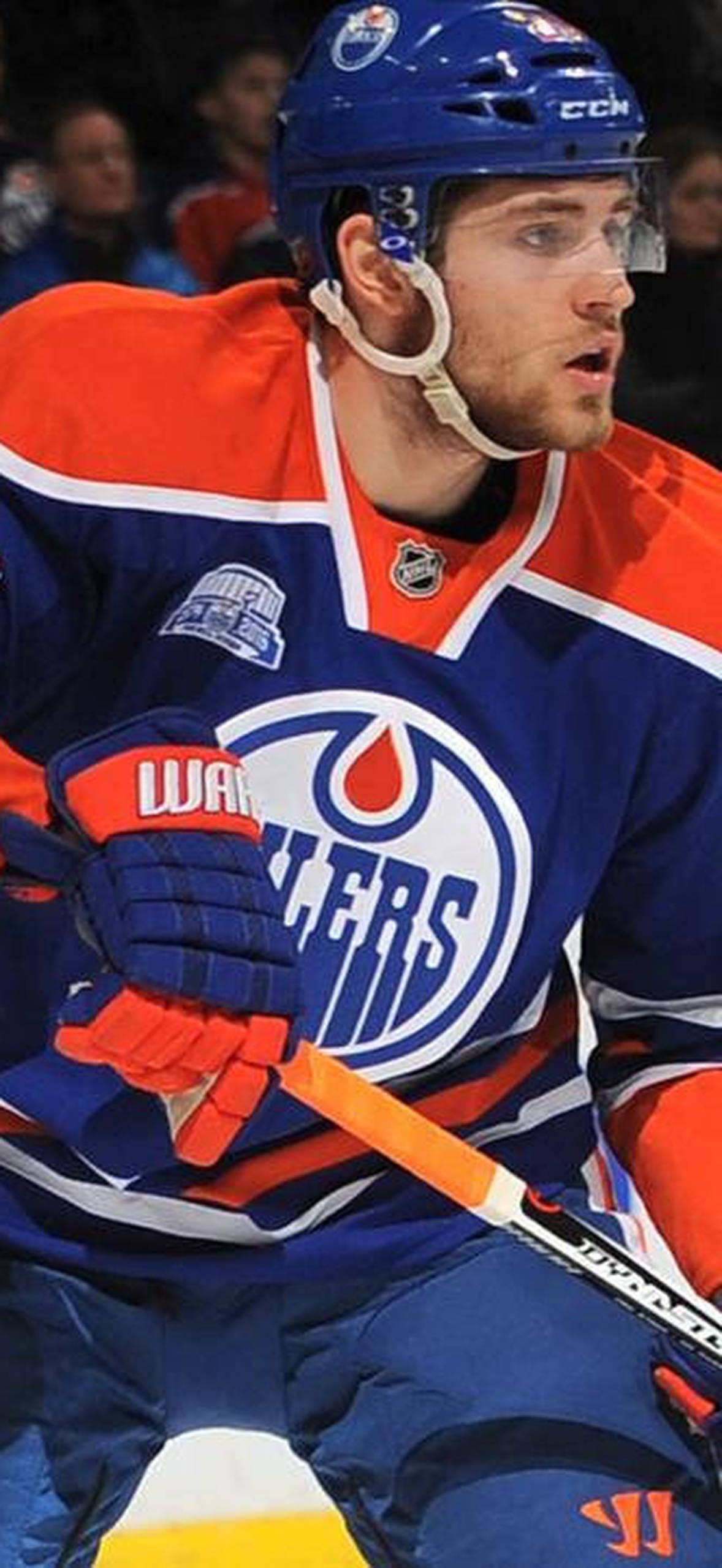 Hockey player in Oilers uniform skating near goal during game.