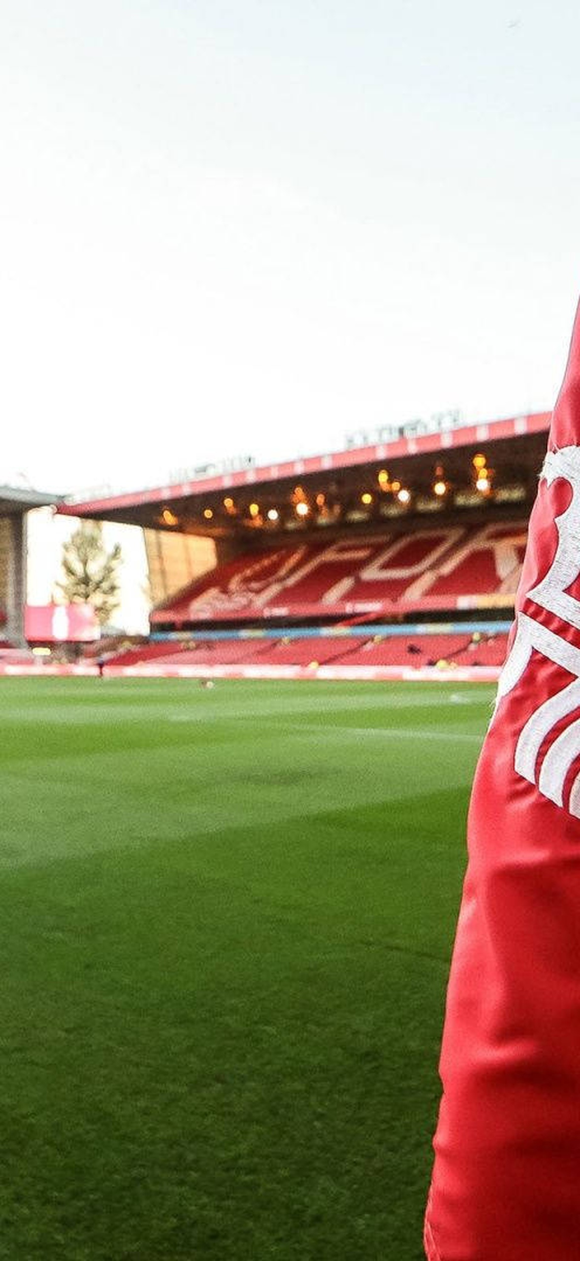 Red Nottingham Forest flag at a football stadium with players training on the pitch.