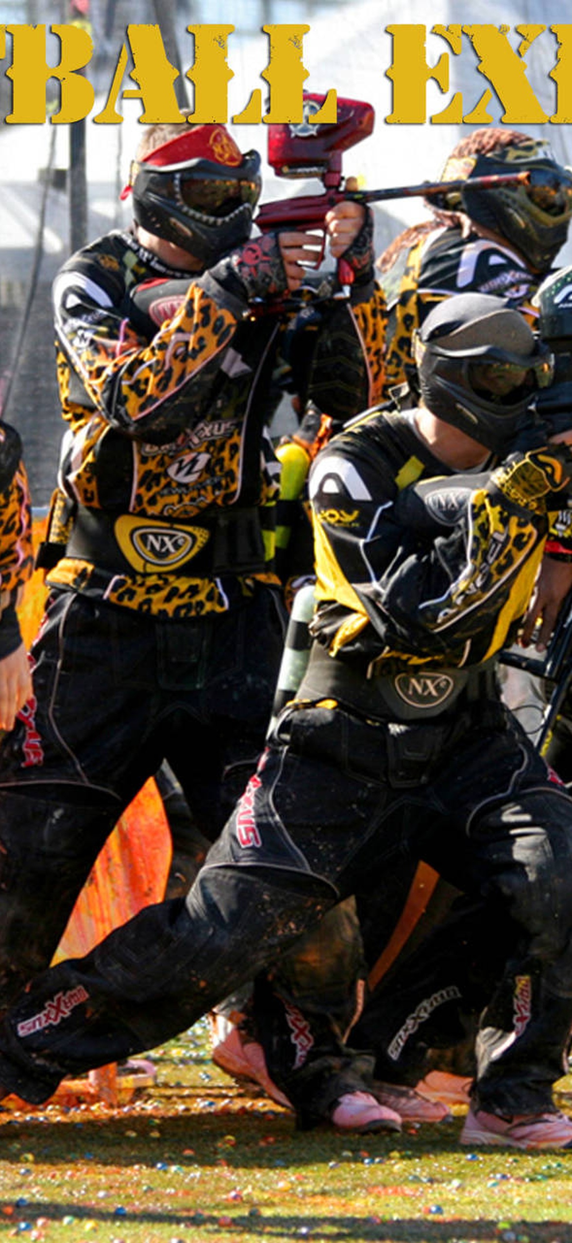 Paintball players in leopard gear sprinting and shooting on a grassy field.