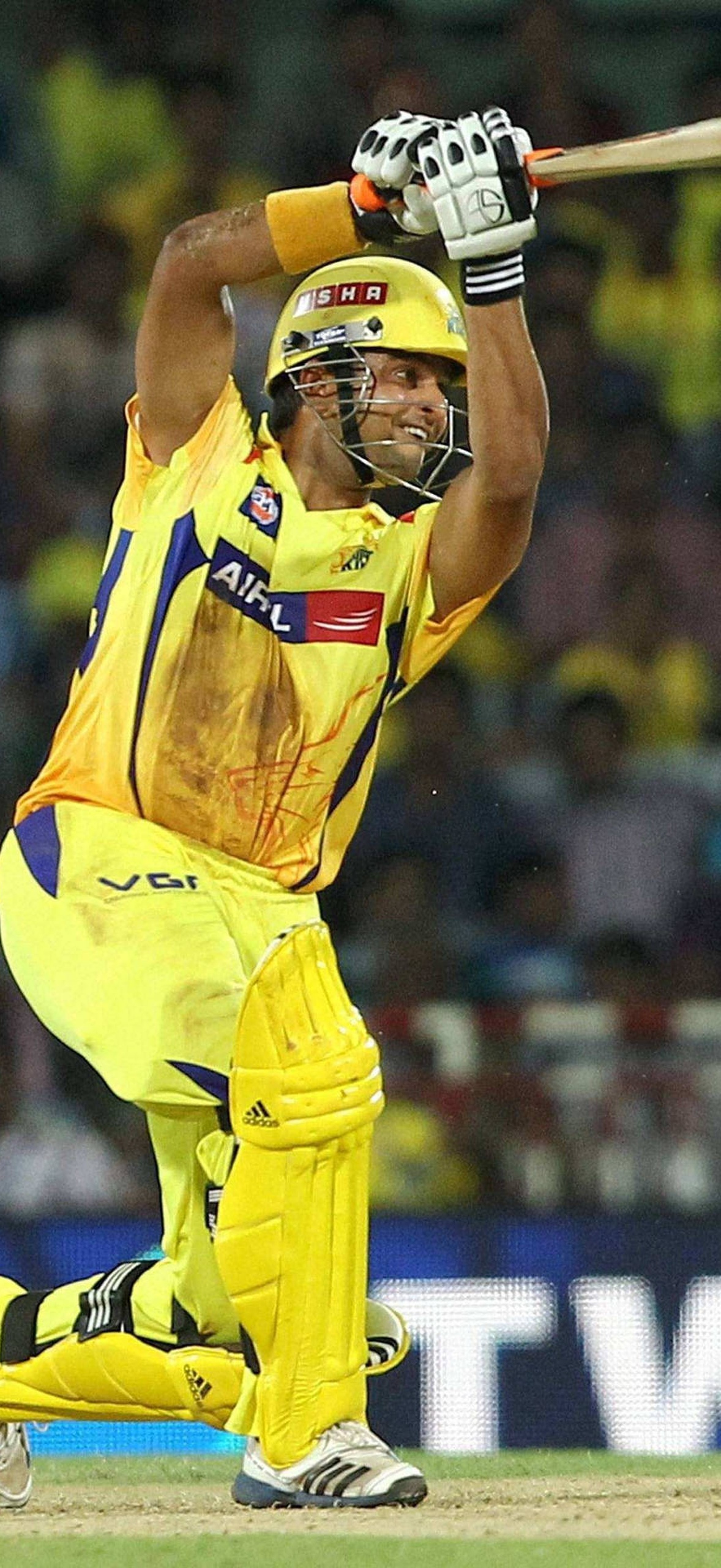 Cricket player swinging bat during night match in yellow uniform.