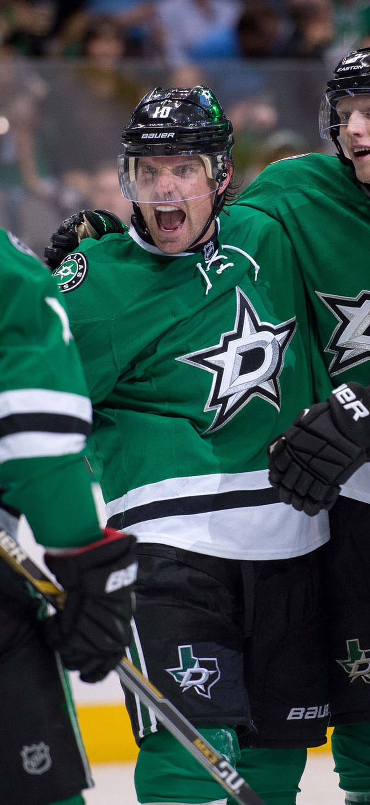Hockey players in green jerseys celebrating a goal on the ice.