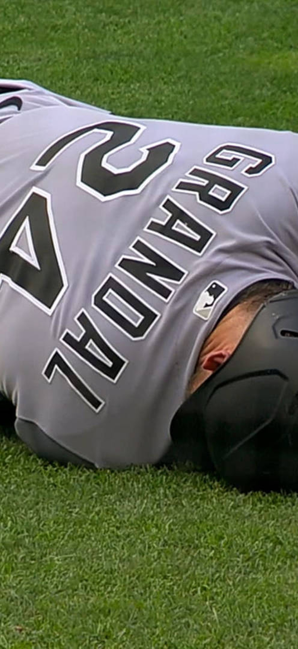 Baseball player injured on field, teammate checking on him.