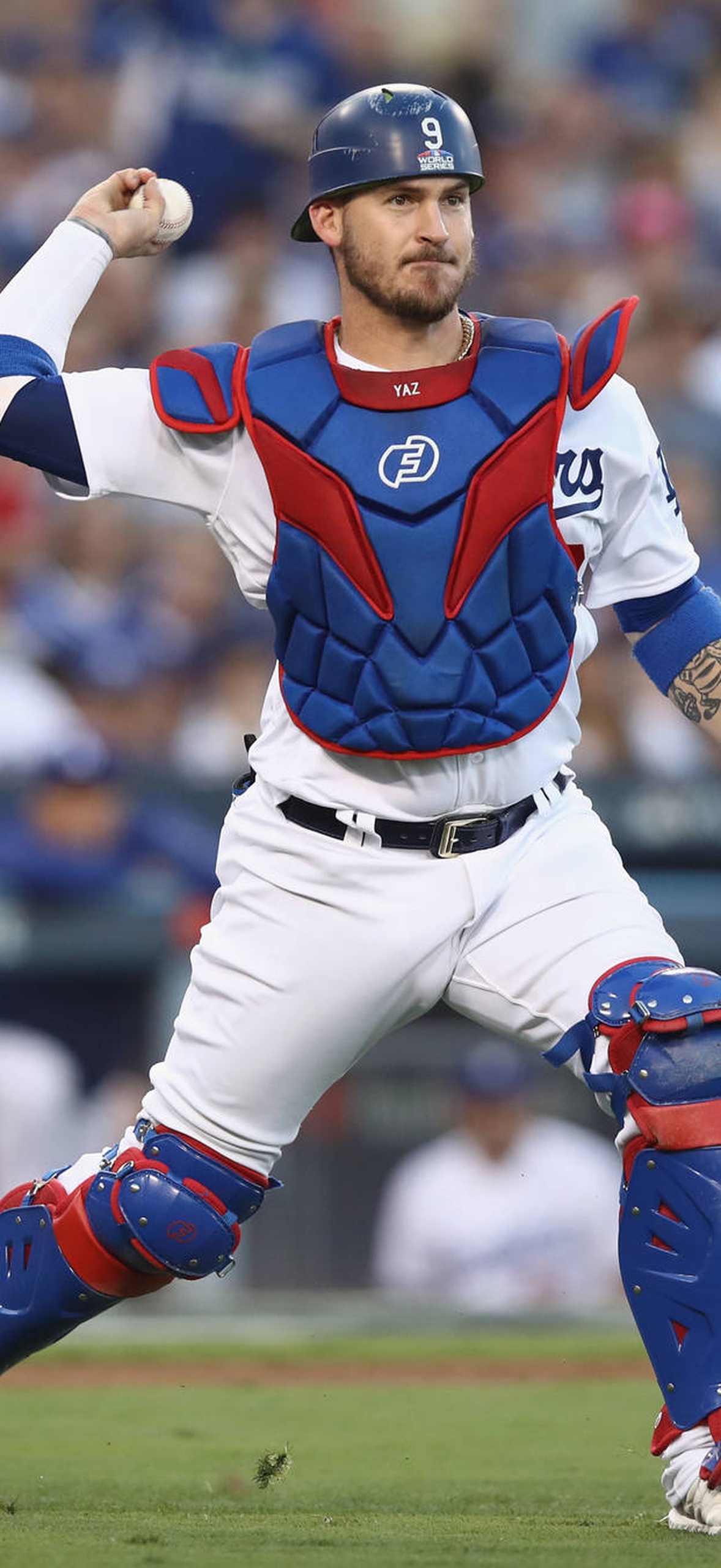 Baseball catcher in full gear throwing a pitch during a game.